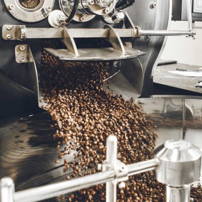 freshly-roasted-coffee-beans-pouring-out-from-roasting-machine-into-cooling-tray (1) (1)